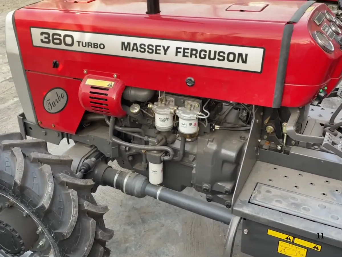 Massey Ferguson MF 360 Turbo 4WD 60HP tractor manufactured by Millat Tractors Pakistan, showing engine side view with turbo marking, fuel filters, and drivetrain components