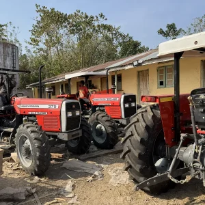 Multiple Massey Ferguson MF 375 tractors by Millat Tractors Pakistan, including 2WD and 4WD models with canopy, parked in a workshop yard during preparation