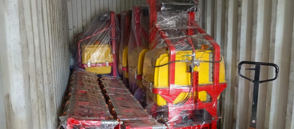 Boom sprayers packed in a container Yellow boom sprayer tanks and red implement frames packed inside a shipping container