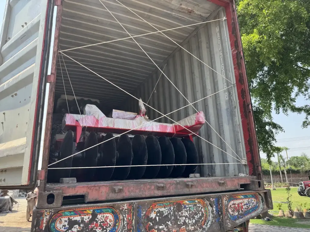 Disc implement packed inside a shipping container Red disc implement and black discs inside an open shipping container