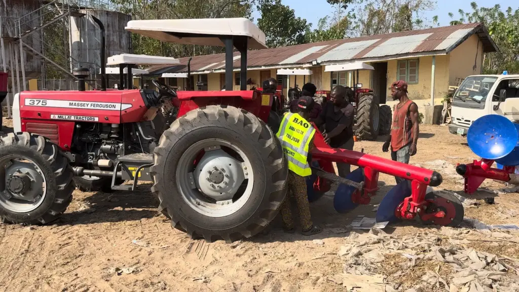 Tractor and disc implement demonstration Red Massey Ferguson tractor attached to a red disc implement with people nearby