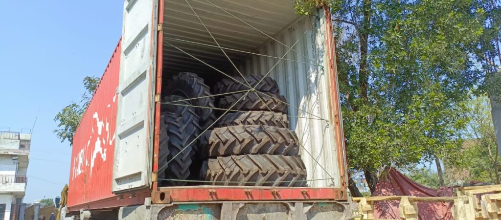 Tractor tyres inside a shipping container Tractor tyres stacked inside an open container beside a wrapped implement
