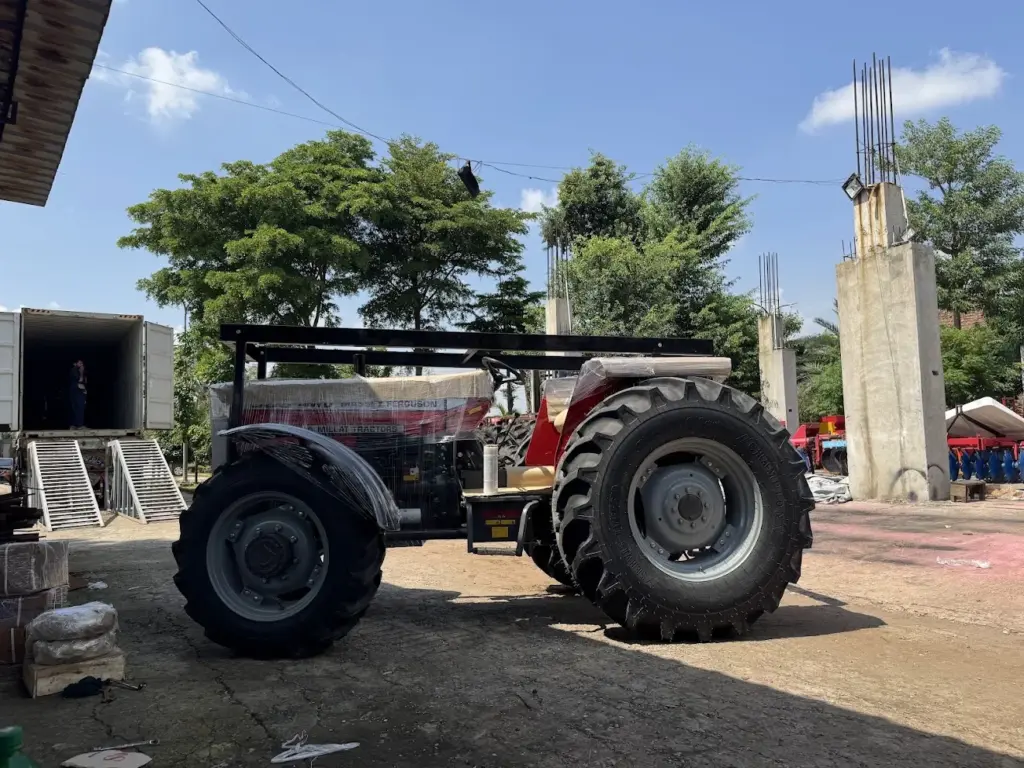 Red tractor with protective wrapping beside container loading ramps